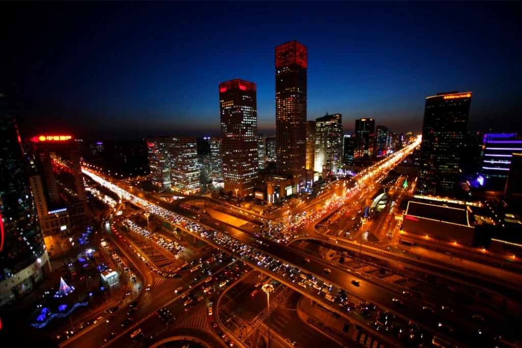 Nighttime view of Beijing’s cityscape, with illuminated skyscrapers and busy highways crossing below.